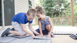Kids installing NewTechWood deck tiles.