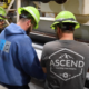 Three employees working together and leaning over an industrial machine