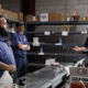 a group of employees standing together in a warehouse as one employee talks to them