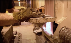 a persons gloved hands use industrial machinery. sparks are present.