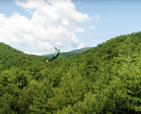 a person going down a zipline over lush green mountains